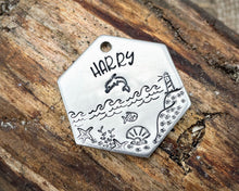 Load image into Gallery viewer, Hexagon dog tag, hand stamped with nautical design, dolphin &amp; lighthouse
