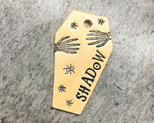 Load image into Gallery viewer, brass coffin dog tag with skeleton hands and spiders
